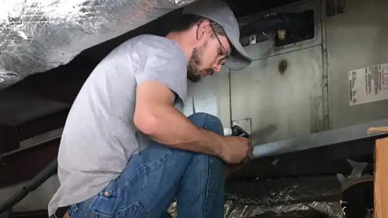 HVAC repairman working on an heating unit in McAlester, OK