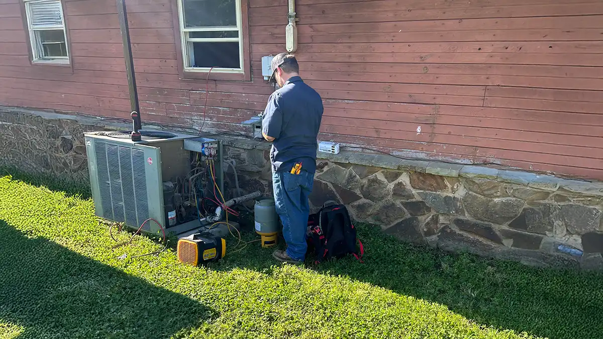 An HVAC repair man performing maintenance on an air conditioning unit