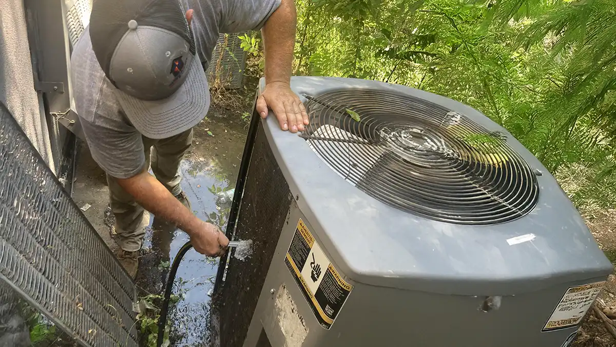 An HVAC repair man cleaning a dirty air conditioning unit